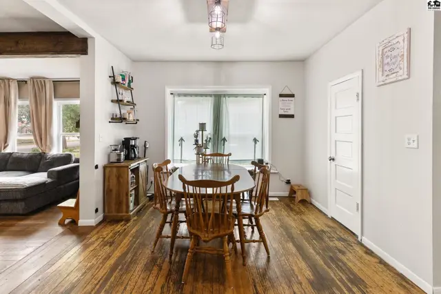 Dining room with rustic wood floors, a large window, and wooden furniture.