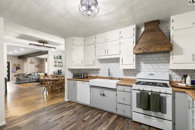 Bright kitchen with white cabinets, subway tile backsplash, farmhouse sink, and wood accents.