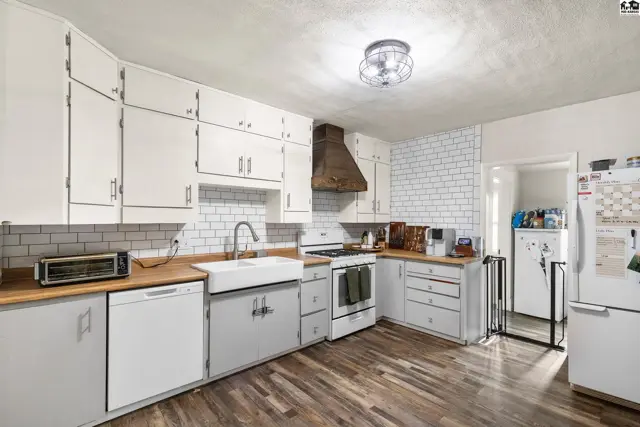 Bright kitchen with white subway tile backsplash, butcher block counters, and white cabinetry.