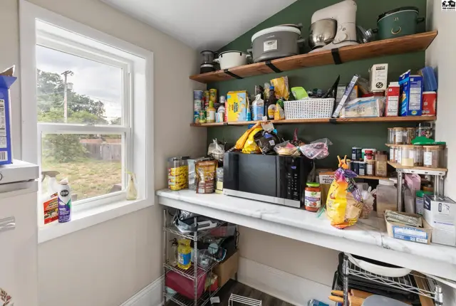 Pantry with white marble countertop, open shelving, and a microwave.