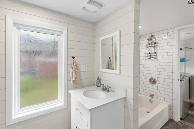 Bright bathroom with white shiplap walls, subway tile shower, and modern vanity.