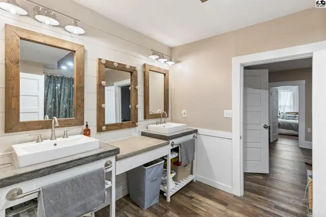 Spacious bathroom with a double vanity featuring rustic wood-framed mirrors and modern vessel sinks.