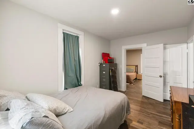 Bedroom with gray walls, hardwood floors, and a doorway opening to another room.