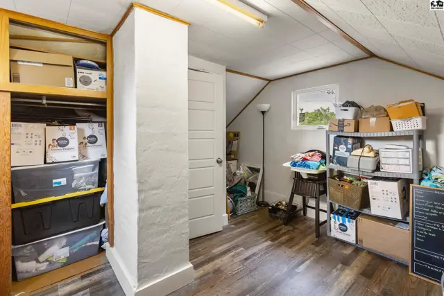 Attic storage room with wood-look flooring, built-in shelving, and sloped ceilings.