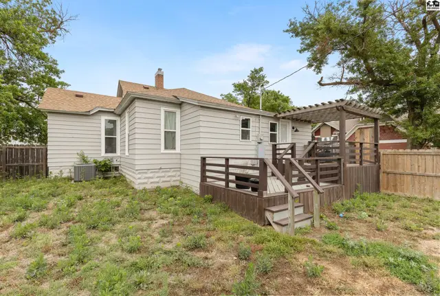 Exterior view of a light gray house with a large wooden deck and pergola.