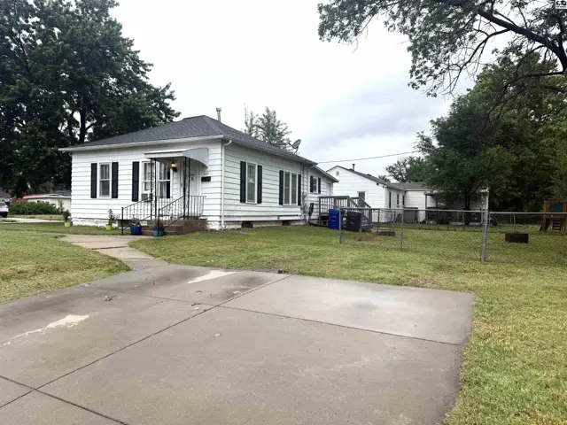 White single-story home with black shutters, a covered porch, and a large grassy yard.