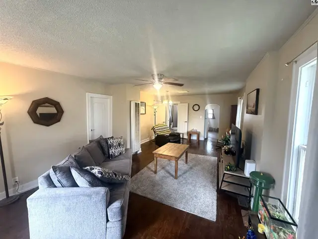 Spacious living room with a gray sectional sofa, hardwood floors, and a light gray rug.