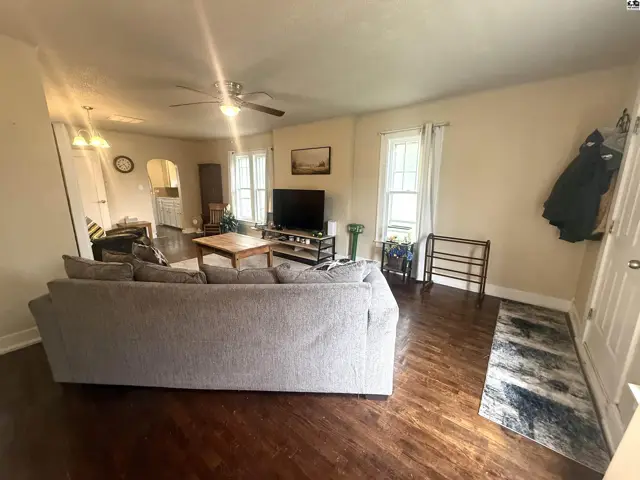 Spacious living room with a large sectional sofa, hardwood floors, and a ceiling fan.