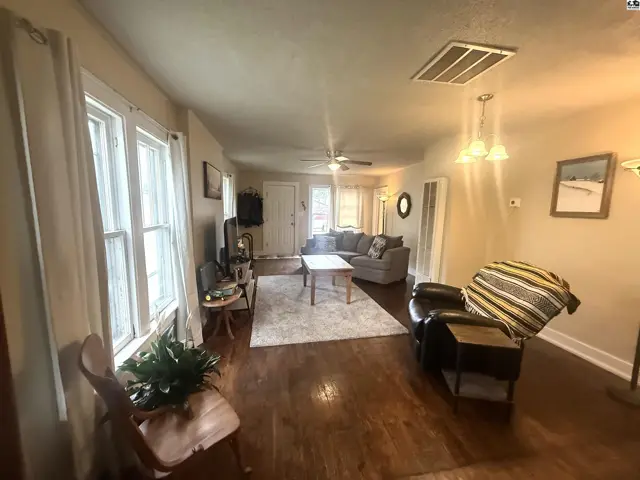 Spacious living room with hardwood floors, large windows, and comfortable seating.