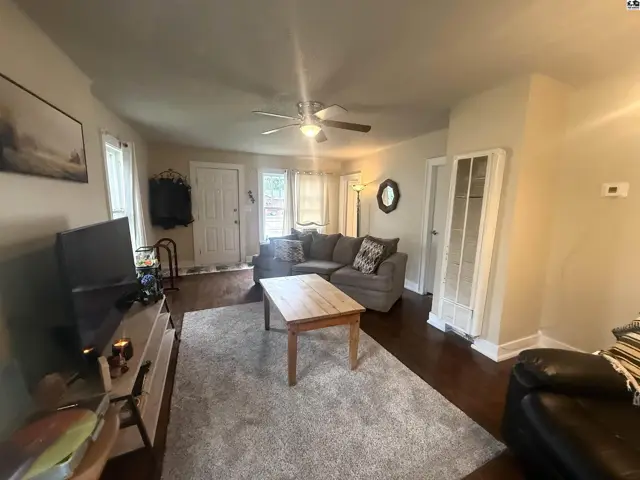 Spacious living room with a gray sectional, wood coffee table, and dark hardwood floors.