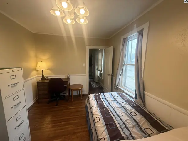 Cozy bedroom with a desk, filing cabinet, and a bed with striped bedding.