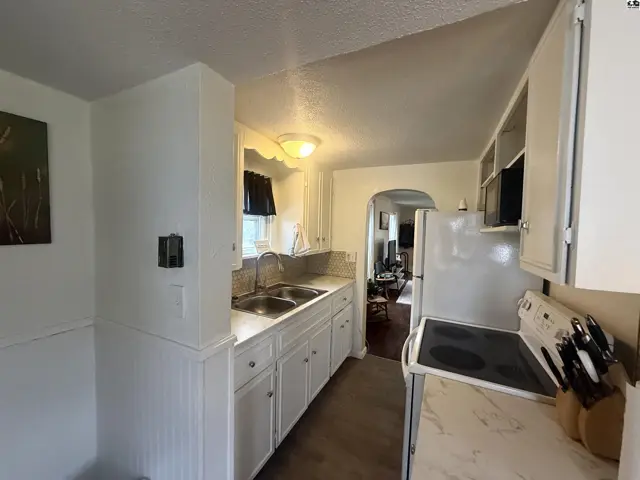 Bright white kitchen with double sink, white cabinets, and a white stove.