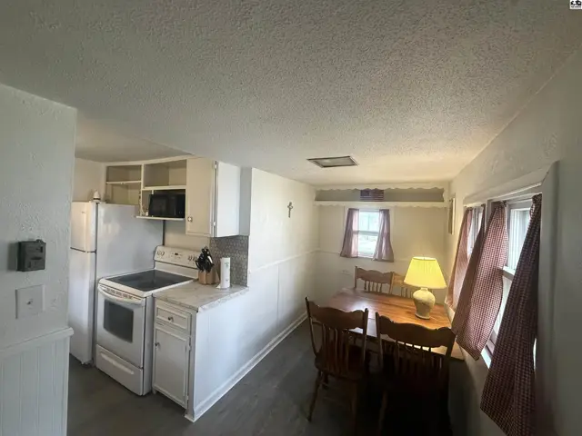 Cozy kitchen and dining area with white cabinets, a stove, and a wooden table with chairs.