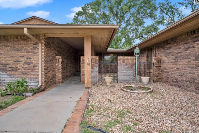 Brick exterior with a covered walkway, gravel landscaping, and a small fenced courtyard.