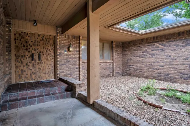 Covered entryway with brick walls, wood ceiling, and a skylight over a gravel courtyard.