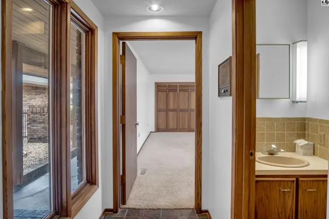 Hallway with wood trim, large windows, and a view into a carpeted room with wood doors.