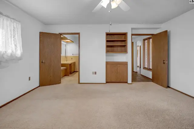 Spacious room with plush carpet, built-in wood cabinetry, and doorways leading to other areas.