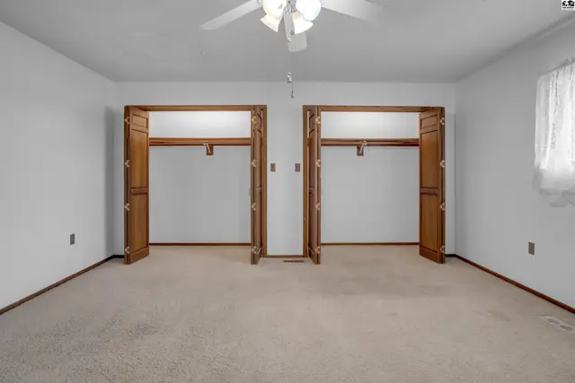 Spacious bedroom with plush carpet and two large, wood-trimmed closets.