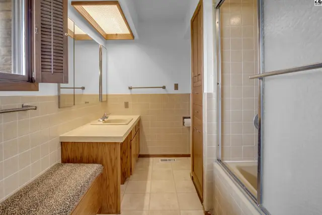 Retro bathroom with tiled walls, wood vanity, and a built-in bench.