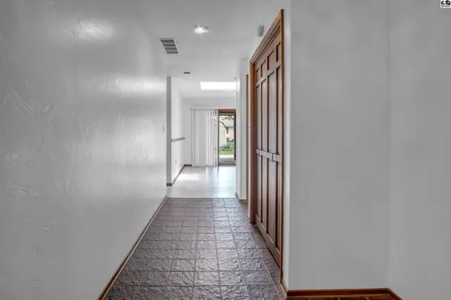 Hallway with textured white walls, tile flooring, and a wooden paneled door.