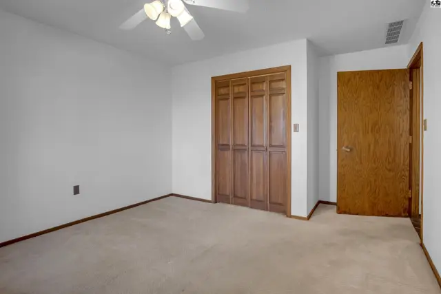 Spacious bedroom with beige carpet, white walls, bi-fold closet doors, and a wood-paneled door.