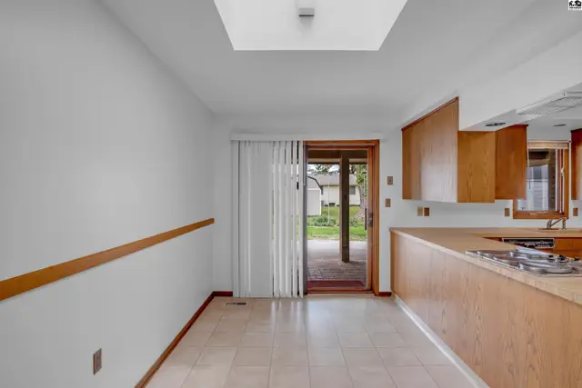 Bright kitchen with wood cabinets, tile floor, and sliding glass doors leading to a patio.