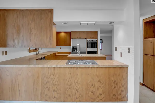 Spacious kitchen with light wood cabinetry, stainless steel appliances, and a gas stovetop on the island.