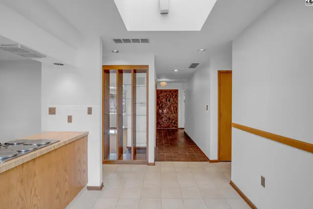 Hallway with tiled floor, wood-paneled walls, and a decorative wall feature.