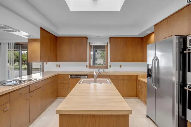 Spacious kitchen with light wood cabinetry, stainless steel appliances, and a large central island.