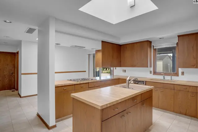 Spacious kitchen with light wood cabinetry, a central island, and a skylight.
