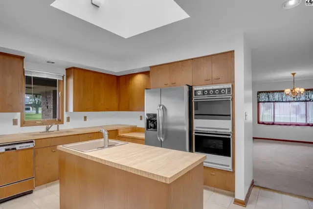 Spacious kitchen with light wood cabinets, stainless steel appliances, and a central island.