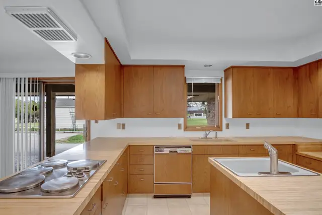 Spacious kitchen with light wood cabinetry, stainless steel appliances, and a large sink.