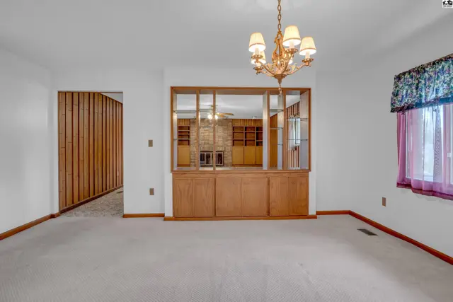 Spacious dining room with plush carpet, wood-paneled wall, and a built-in display cabinet.