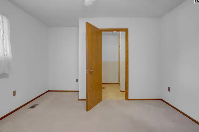 Bedroom with neutral carpet, white walls, and a light wood door opening to a hallway.