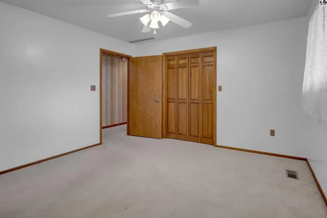 Spacious bedroom with neutral carpet, white walls, and a bi-fold closet door.