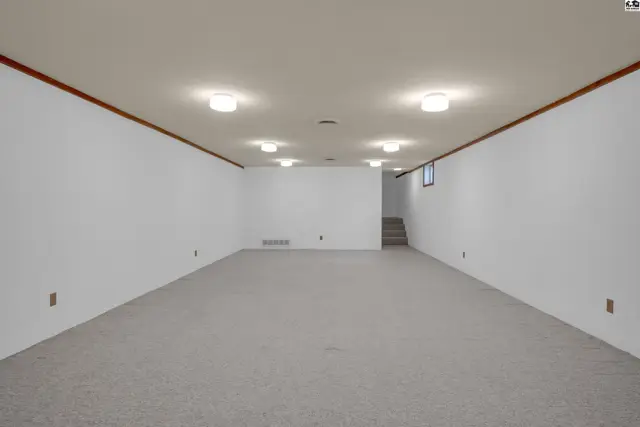 Spacious unfinished basement with neutral carpet, white walls, and recessed lighting.