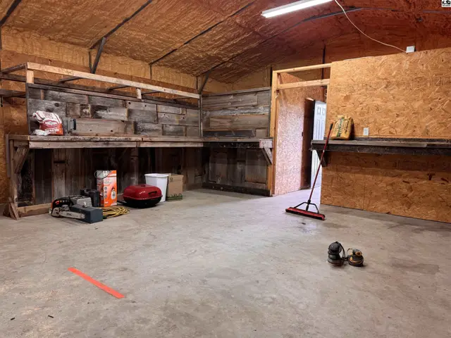 Spacious workshop with concrete floors, rustic wood paneling, and built-in shelving.