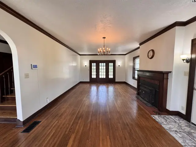 Spacious living room with hardwood floors, fireplace, and French doors leading to another area.