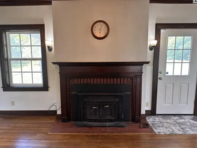 Living room features a dark wood fireplace mantel, wood floors, and a white door.