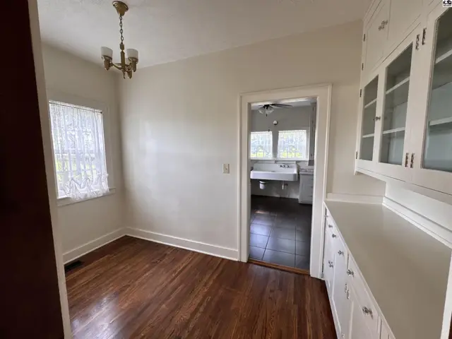 Dining area with hardwood floors, built-in cabinetry, and view into a kitchen with a sink.