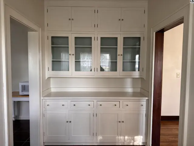 Built-in white cabinetry with glass-front upper cabinets and wood floors.