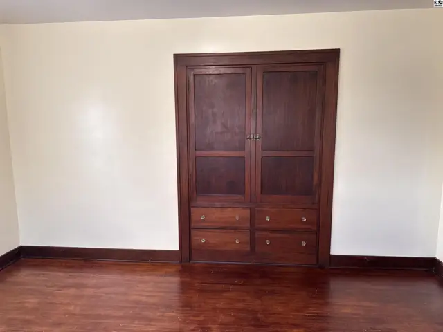 Built-in dark wood cabinetry with drawers and paneled doors complements the rich hardwood floors.