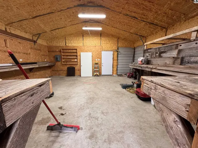 Spacious workshop with concrete floors, wooden workbenches, and insulated ceiling.