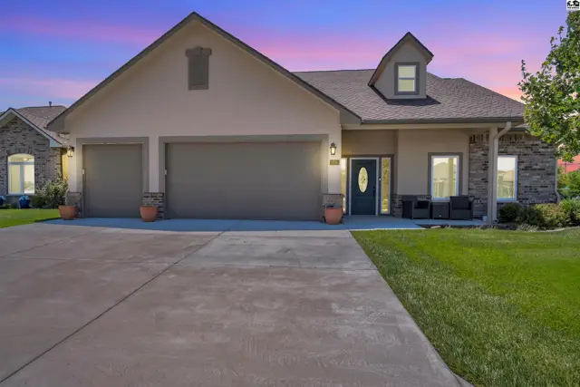 This home features a stucco exterior, stone accents, a three-car garage, and a covered front porch.