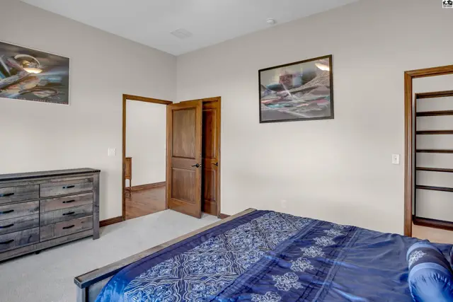 This bedroom features a dresser, a bed with blue bedding, and a closet with shelving.