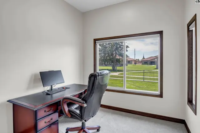 This room features a desk, chair, and a large window overlooking a grassy yard.