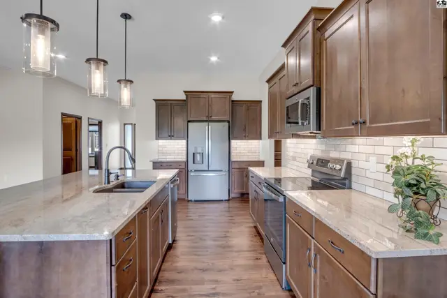 Spacious kitchen features granite countertops, stainless steel appliances, and ample wood cabinetry.