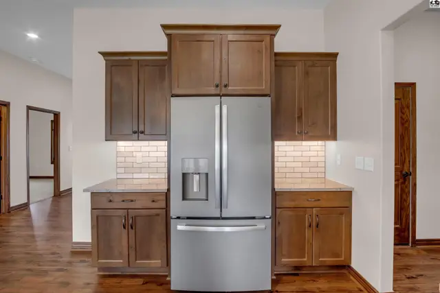 Stainless steel refrigerator is flanked by dark wood cabinetry and white subway tile backsplash.