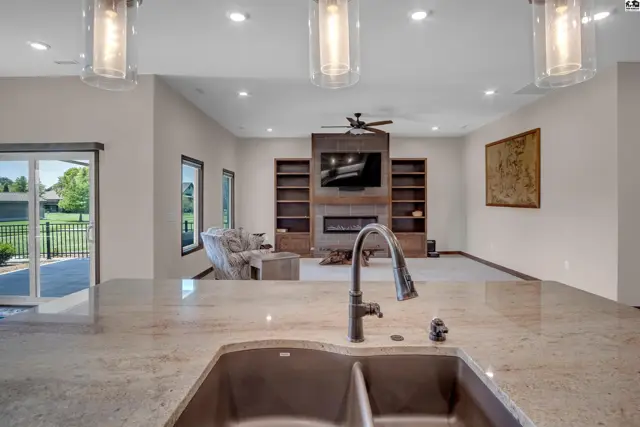 Spacious living area with fireplace, built-in shelving, and large windows.