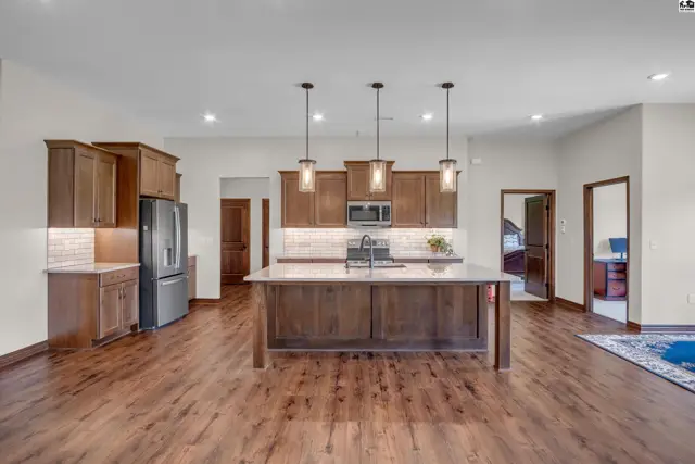 Spacious kitchen features dark wood cabinetry, a large island, and stainless steel appliances.